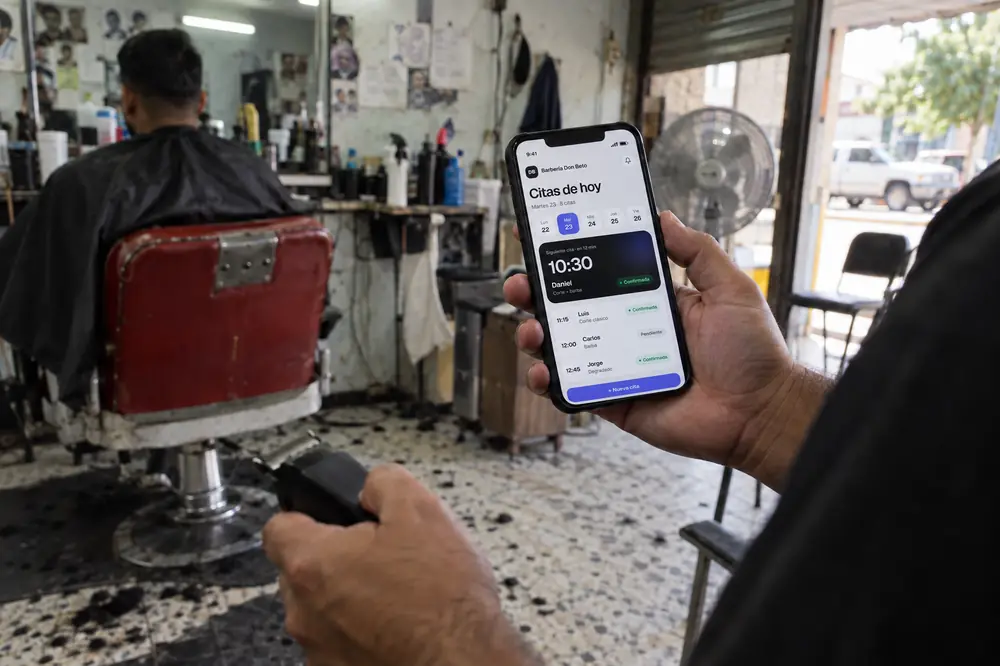 Ejemplo: un barbero revisa en su celular las citas de hoy mientras su cliente espera en el sillón